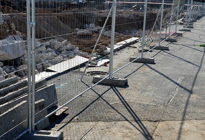 perimeter of temporary fence panels surrounding a festival area with colorful tents